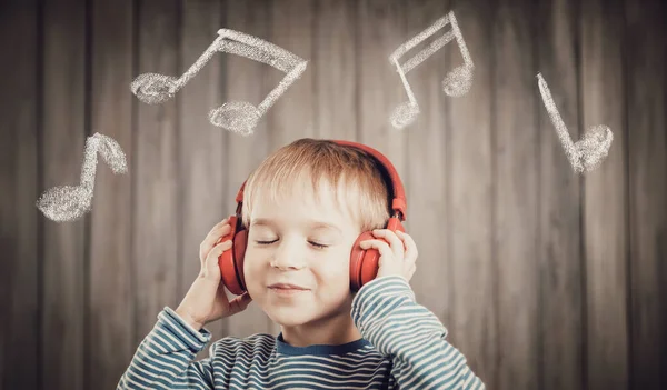 Kleiner Junge auf hölzernem Hintergrund mit roten Kopfhörern — Stockfoto