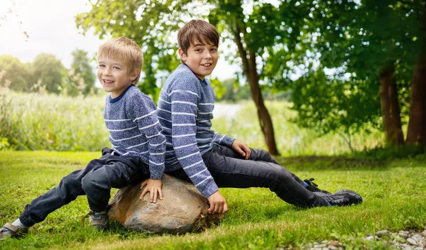 Två underbara bröder sitter i parken med blommor kramas — Stockfoto