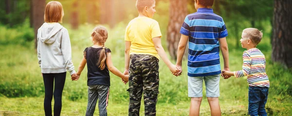 Pojkar och flickor som står i skogen och håller varandra i handen på sommarlovet — Stockfoto