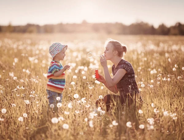 Νεαρή γυναίκα με ένα αγόρι φυσάει φυσαλίδες — Φωτογραφία Αρχείου