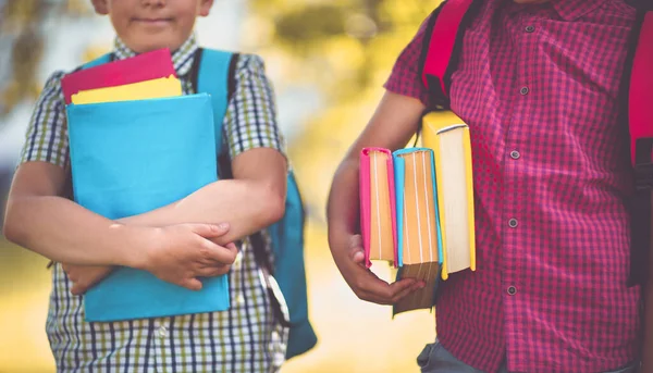 Niños con mochilas de pie en el parque cerca de la escuela —  Fotos de Stock