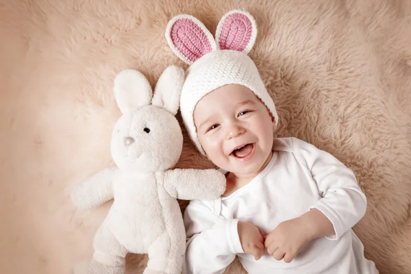 Ett år gammal baby liggande i kanin hatt på lamm ull — Stockfoto