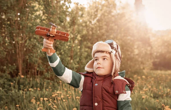 Мальчик играет в шляпу летчика со старым самолетом — стоковое фото