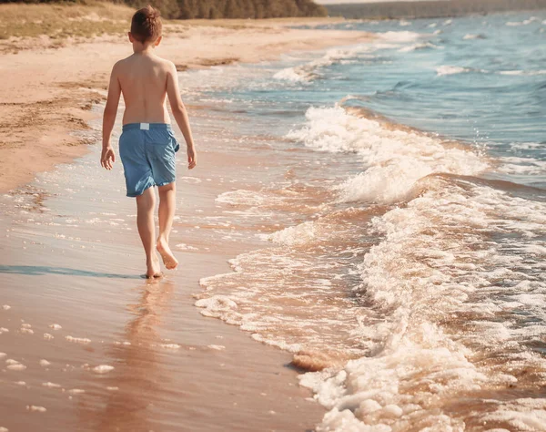 Мальчик босиком прыгает по пляжу в воде — стоковое фото