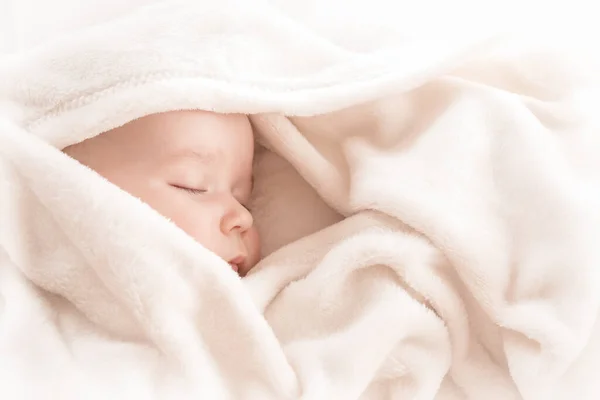 Bebé durmiendo cubierto con manta blanca suave — Foto de Stock