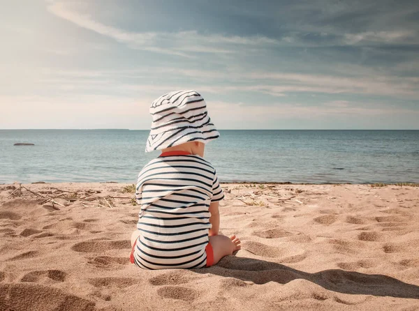 Liten pojke sitter på stranden på sommardagen — Stockfoto