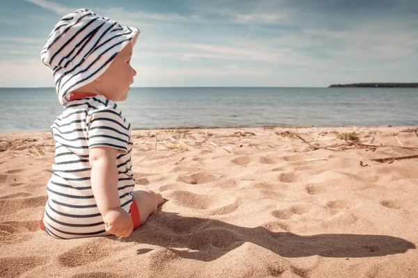 Liten pojke sitter på stranden på sommardagen — Stockfoto