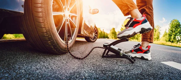 Autista utilizzando una pompa a pedale per gonfiare un pneumatico — Foto Stock
