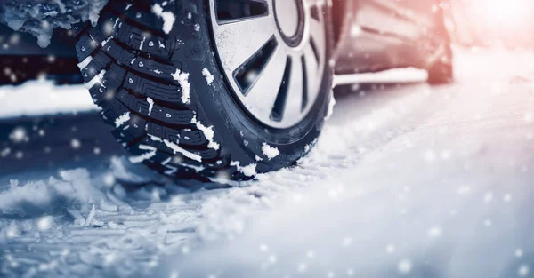 Närbild av bildäck på vintern väg täckt med snö i snöfall i solig dag — Stockfoto
