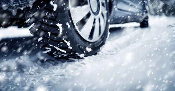 Primer plano del neumático del coche en el camino de invierno cubierto de nieve en las nevadas —  Fotos de Stock