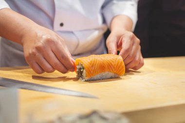 Japon Suşi rulo yapmak eller yemek. Japon Şef hazırlanıyor suşi nori yaprak üzerinde pirinç ile rulo.