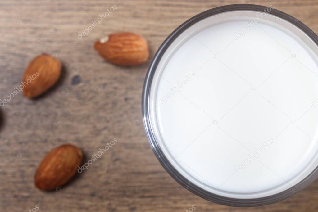Photo of homemade almond milk with almond on a wooden table.