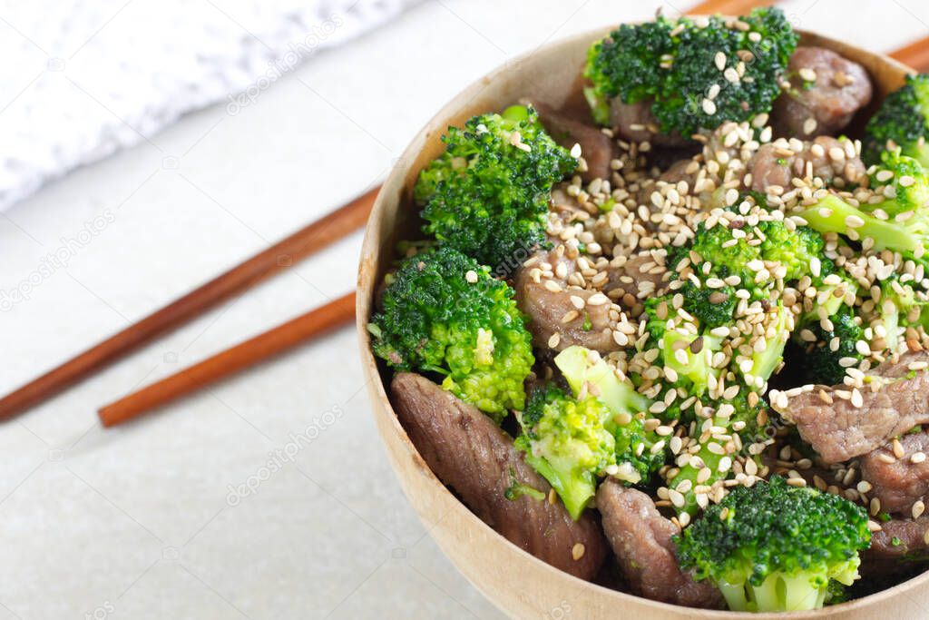Photo of Beef and Broccoli with ginger in wooden bowl. Traditional chinese recipe.