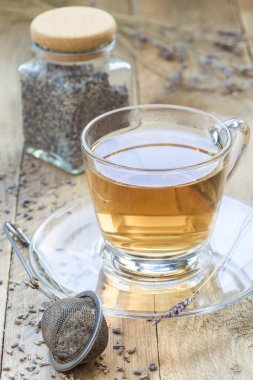 Sağlıklı bitkisel lavanta çayı ve arka planda lavanta çiçekleri, dikey