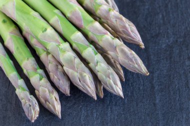 Koyu bir arka planda bir sürü taze kuşkonmaz, yatay.
