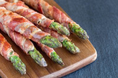 Sağlıklı aperatif, ahşap tahtaya sarılı yeşil kuşkonmaz, yatay, kopyalama alanı.