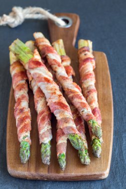 Sağlıklı meze, ahşap tahtaya sarılı yeşil kuşkonmaz, dikey.