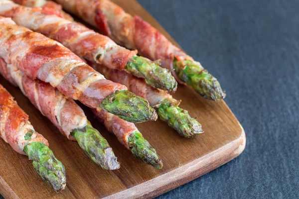 Sağlıklı aperatif, ahşap tahtaya sarılı yeşil kuşkonmaz, yatay, kopyalama alanı.