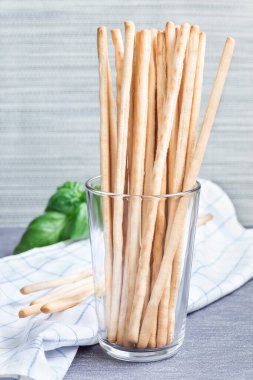 Geleneksel İtalyan aperatifi Grissini ekmek çubukları arka planda fesleğen yapraklı, dikey