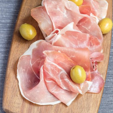 Tahta üzerinde yeşil zeytinli jambon, kare şeklinde.