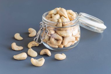 Koyu gri arka planda, cam kavanozda kaju fıstığı, yatay.