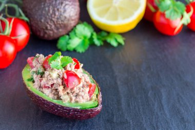 Ton balıklı salata, avokado, domates, kişniş ve limon suyu avokado kaselerinde servis edilir.
