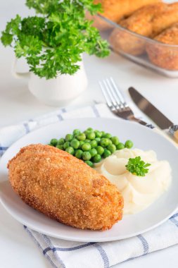 Tavuk Kiev, Ukrayna mutfağı. Tereyağı ve otla doldurulmuş ekmek kırıntıları içinde tavuk pirzolası, patates püresi ve yeşil bezelye ile servis edilmiş, beyaz bir tabakta, dikey