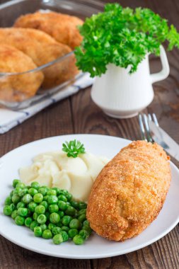 Tavuk Kiev, Ukrayna mutfağı. Tereyağı ve otla doldurulmuş ekmek kırıntıları içinde tavuk pirzolası, patates püresi ve yeşil bezelye ile servis edilmiş, beyaz bir tabakta, dikey