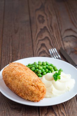 Tavuk Kiev, Ukrayna mutfağı. Tereyağı ve otla doldurulmuş ekmek kırıntıları içinde tavuk pirzolası, patates püresi ve yeşil bezelye ile servis edilmiş, dikey, kopyalama alanı