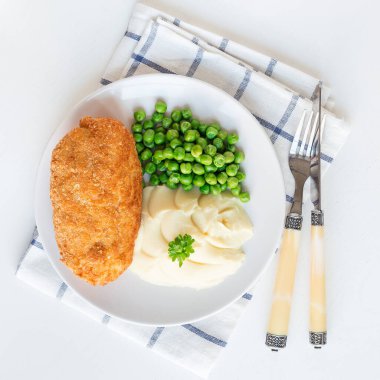 Tavuk Kiev, Ukrayna mutfağı. Tereyağı ve otla doldurulmuş ekmek kırıntılarıyla doldurulmuş tavuk pirzolası, patates püresi ve yeşil bezelyeyle servis edilmiş, beyaz arka planda, kare formatta, üst manzara