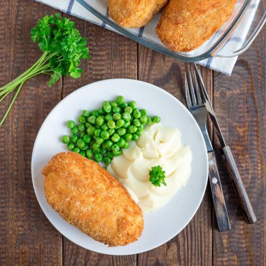 Tavuk Kiev, Ukrayna mutfağı. Tereyağı ve otla doldurulmuş ekmek kırıntıları içinde tavuk pirzolası, patates püresi ve yeşil bezelye ile servis edilir, kare format, üst görünüm