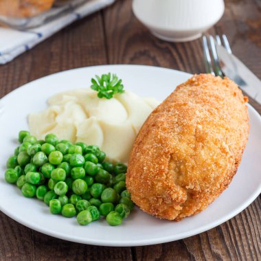 Tavuk Kiev, Ukrayna mutfağı. Tereyağı ve otla doldurulmuş ekmek kırıntıları içinde tavuk pirzolası, patates püresi ve yeşil bezelye ile servis ediliyor, kare format.