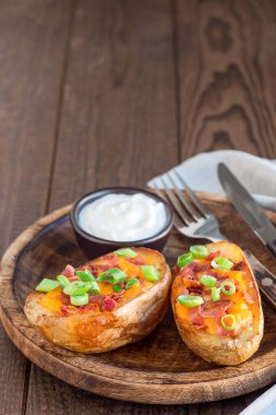 Fırınlanmış patates kabukları çedar peyniri ve pastırma, soğan ve ekşi krema ile süslenmiş, dikey, kopyalama alanı