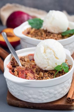 Erikli turta veya yulaf ve baharatlı erik gevreği, vanilyalı dondurma topu ile servis edilir, bir fırın kabında, dikey