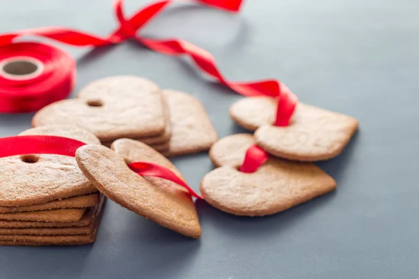 Holiday sweets. Swedish christmas gingerbread cookies pepparkakor, decorated with a red ribbon, on dark gray background, horizontal