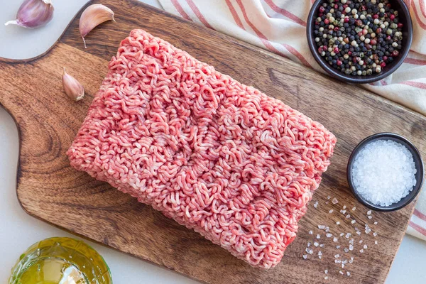 Minced meat from pork and beef. Ground meat with ingredients for cooking on a wooden board, horizontal, top view