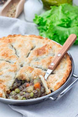 Mercimek, mantar, patates, havuç ve yeşil bezelyeli vejetaryen turtası, kabartma kabıyla kaplı, dikey.