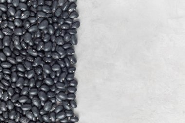 Gri beton arkaplanda kuru siyah fasulyeler, yatay, üst görünüm, boşluğu kopyala