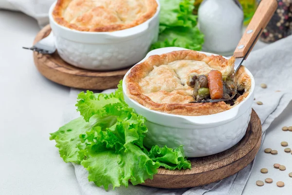 stock image Vegetarian pot pie with lentil, mushroom, potato, carrot and green peas, covered with puff pastry, in baking dish, horizontal