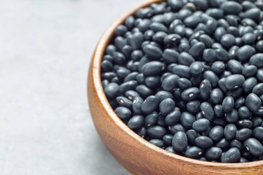 Gri beton arka plan, yatay, kopyalama alanı üzerinde ahşap bir kasede siyah fasulye.