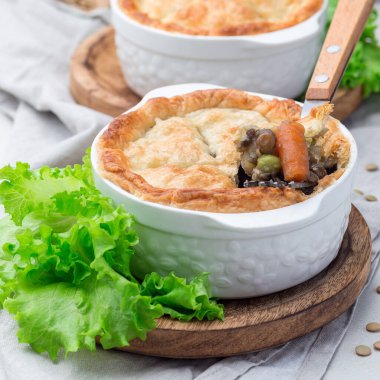 Mercimek, mantar, patates, havuç ve yeşil bezelyeli vejetaryen turtası. Kabartma kabında, kare şeklinde.