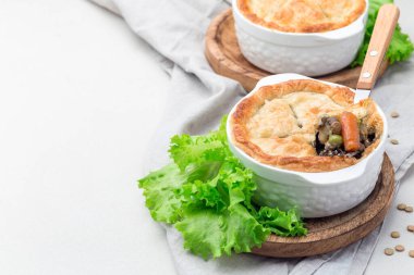 Mercimek, mantar, patates, havuç ve yeşil bezelyeyle kaplı vejetaryen turtası. Kabartma kabında, yatay, kopyalama alanında.