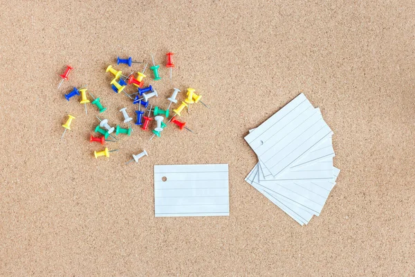 Cork memory board with blank peaces of paper and heap of pins, horizontal