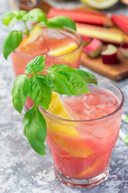 Limonata, limon, köpüklü su ve fesleğenle ferahlatıcı bardakta, dikey, yakın plan.