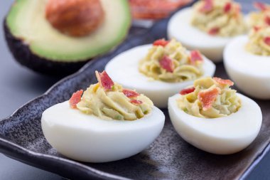 Avokado, yumurta sarısı ve mayonez ile doldurulmuş jambonla süslenmiş yumurtalar.