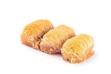 Üç Yunan hamur işi Kataifi, dilimlenmiş fileto hamuru, badem fıstığıyla doldurulmuş, bal şurubu, beyaz bir sosa izole edilmiş.