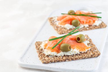 Füme somon ve krem peynirli sandviç ince çoklu tohum ekmeği, yeşil soğan ve zeytinlerle süslenmiş, yatay, kopyalanmış spac