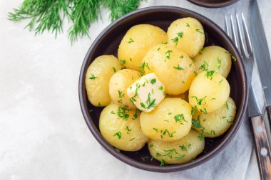 New young boiled  potato topped with melted butter and chopped dill in a ceramic bowl, horizontal,  top view, copy space clipart
