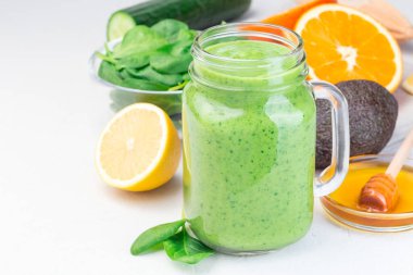 Yeşil detoks smoothie with avokado, ıspanak, salatalık, portakal, limon ve bal, in a glass jar, horizontal, copy space, close