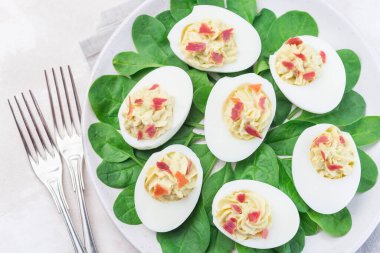 Avokado, yumurta sarısı ve mayonez ile doldurulmuş yumurtalar, pastırmayla süslenmiş, ıspanak yapraklarıyla süslenmiş, yatay, üst manzara